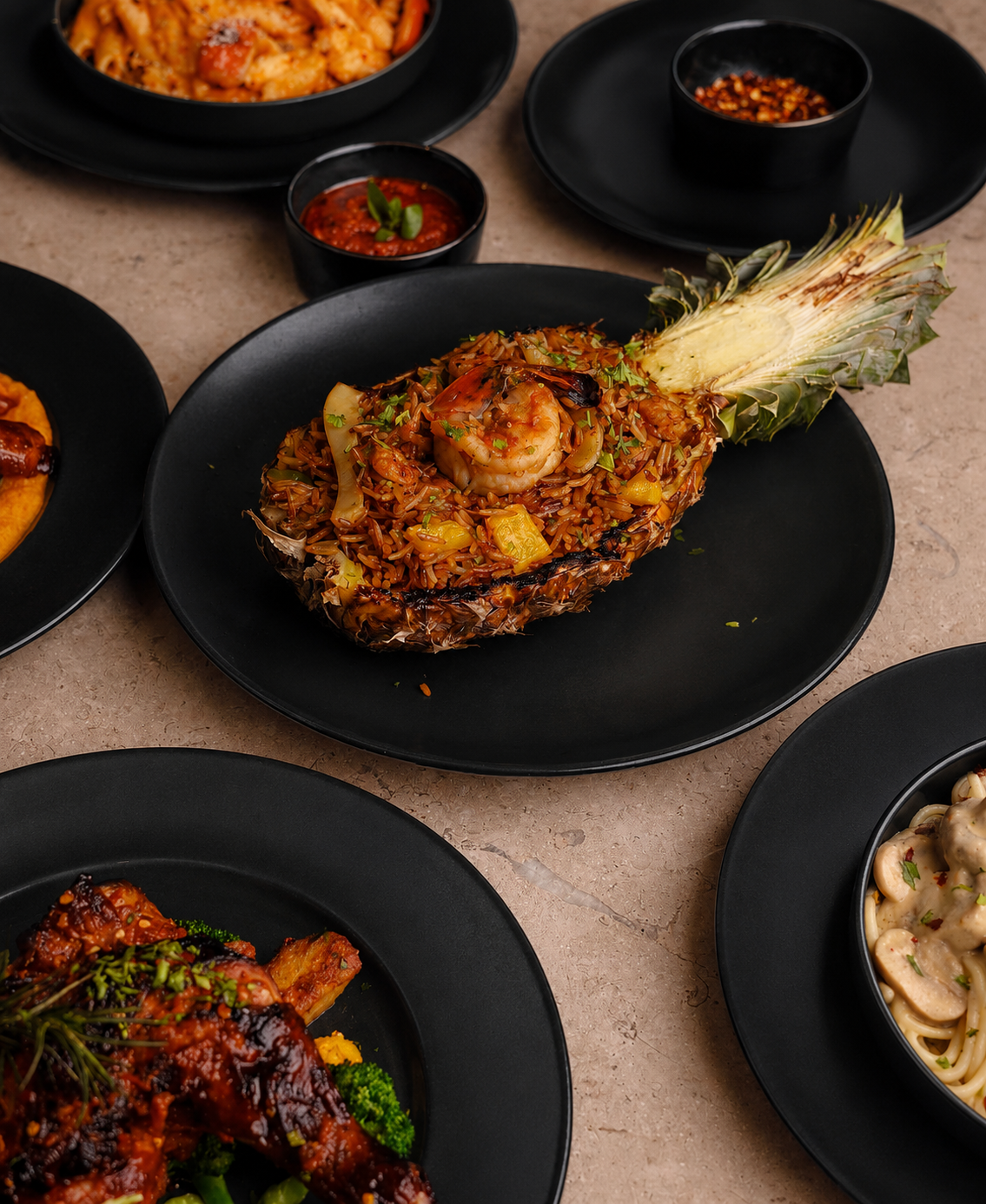 Grilled pineapple fried rice studded with prawns, served in a hollowed pineapple alongside an array of shared plates.